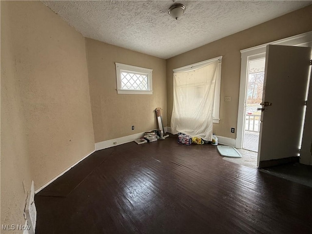 spare room featuring a textured ceiling, baseboards, and wood finished floors