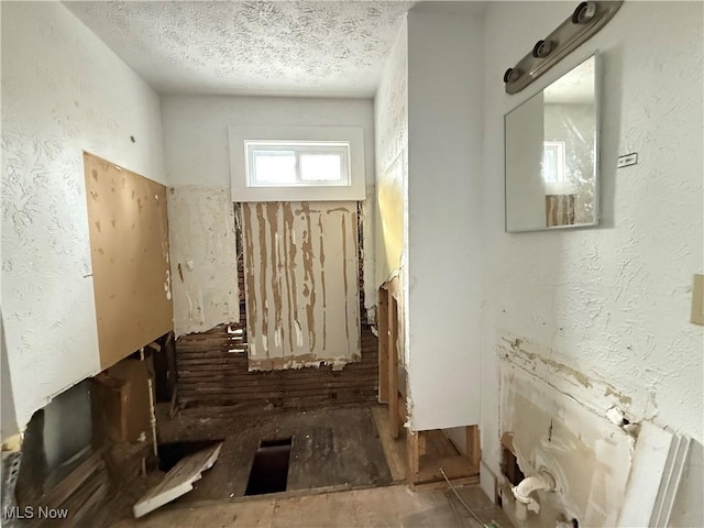 hall with a textured wall and a textured ceiling