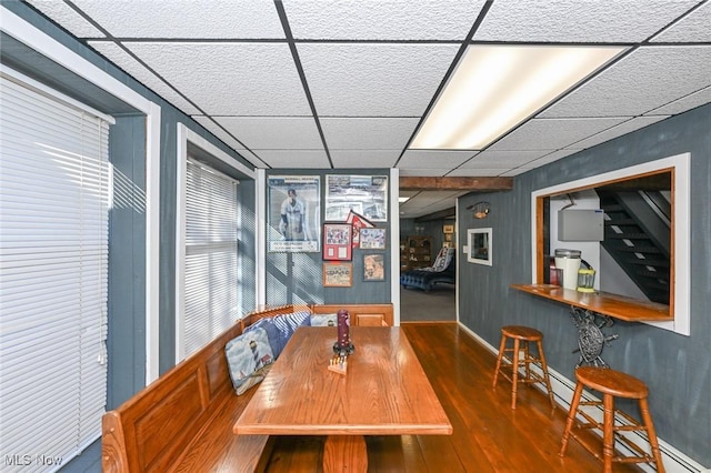 dining room with a paneled ceiling, baseboard heating, and wood finished floors