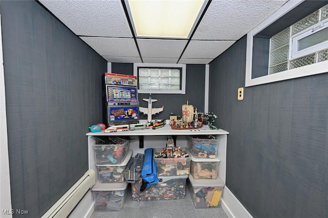 interior space with baseboard heating, a drop ceiling, and baseboards