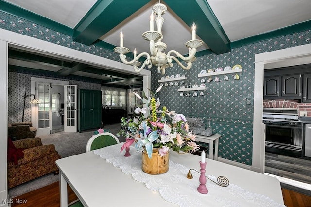 dining area with wood finished floors, beam ceiling, a notable chandelier, and wallpapered walls