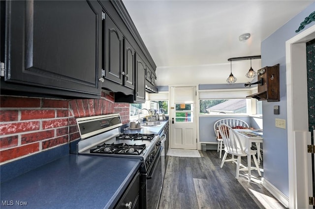 kitchen with dark wood-style flooring, tasteful backsplash, a sink, stainless steel gas range, and baseboards