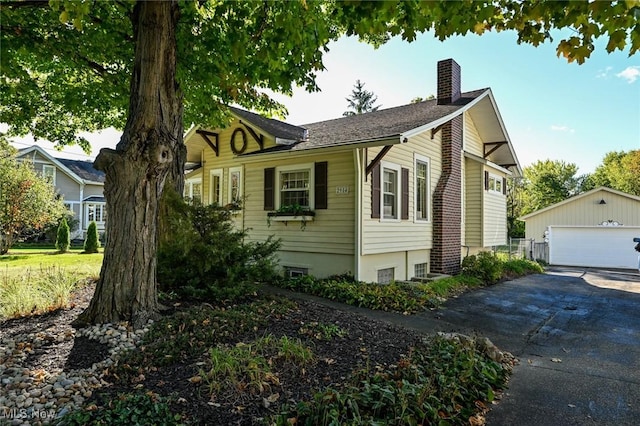 view of front facade featuring an outdoor structure, a chimney, and a detached garage