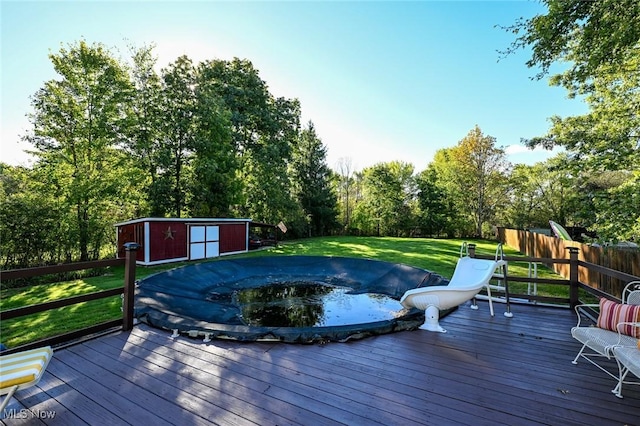 deck featuring a yard, a hot tub, and an outdoor structure