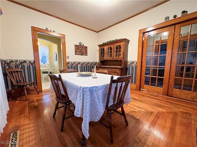 dining space featuring hardwood / wood-style flooring, visible vents, ornamental molding, and french doors