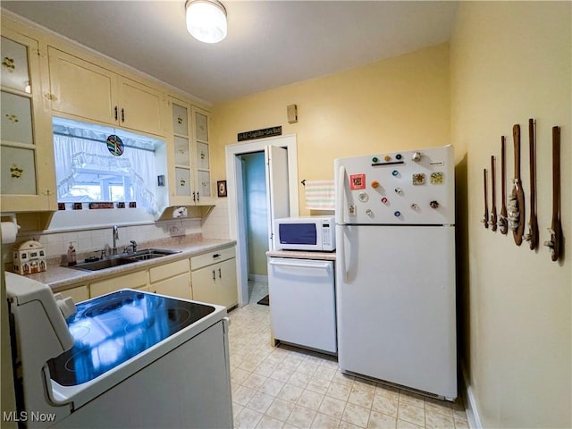 kitchen featuring light countertops, white appliances, backsplash, and a sink