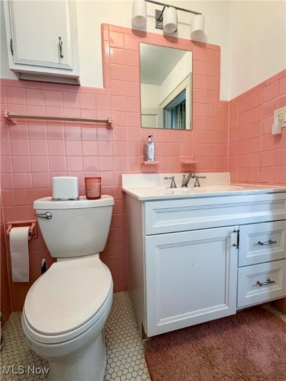 bathroom with toilet, tile patterned floors, tile walls, and vanity