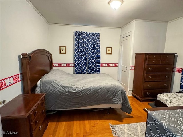 bedroom with wood finished floors and crown molding