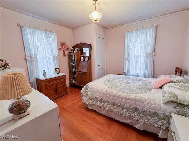 bedroom featuring light wood-style flooring and crown molding