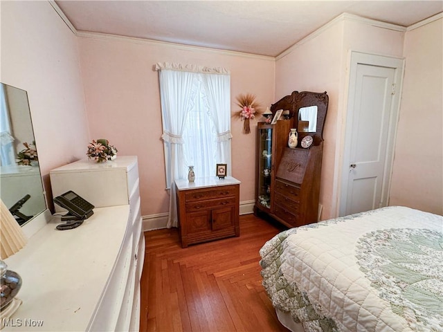 bedroom featuring baseboards, ornamental molding, a baseboard radiator, and light wood-style floors