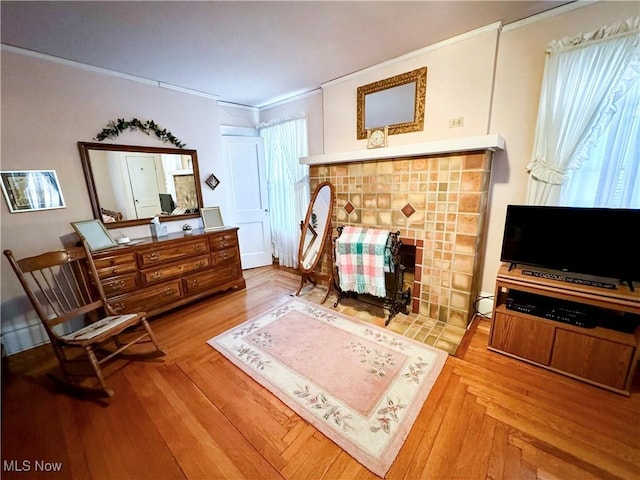 sitting room with parquet floors, a tile fireplace, and crown molding