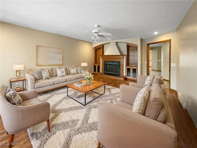 living room featuring ceiling fan, a glass covered fireplace, wood finished floors, and recessed lighting