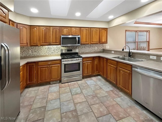 kitchen with a skylight, brown cabinetry, decorative backsplash, stainless steel appliances, and a sink