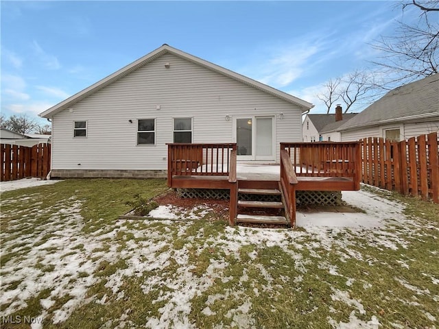 snow covered rear of property with a deck and fence