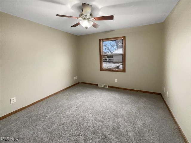 carpeted empty room with a ceiling fan, visible vents, and baseboards