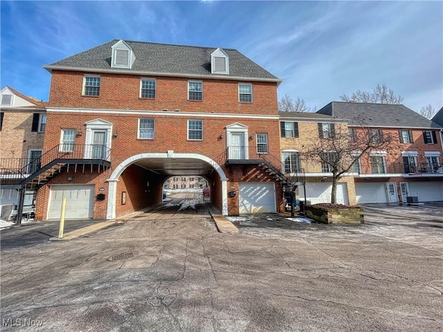 view of front facade featuring a garage, brick siding, stairway, and central AC unit