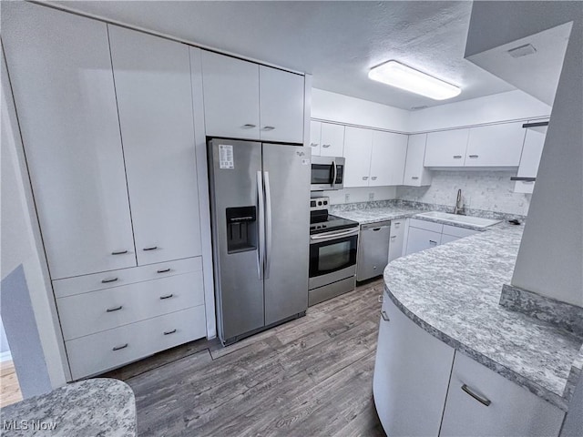 kitchen featuring white cabinetry, appliances with stainless steel finishes, light countertops, and wood finished floors