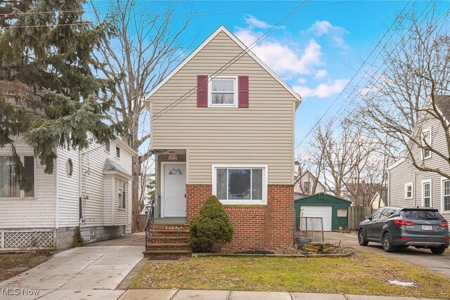 11915 Franklin Blvd, Lakewood, OH 44107 - view of front facade featuring entry steps, a garage, concrete driveway, an outbuilding, and brick siding