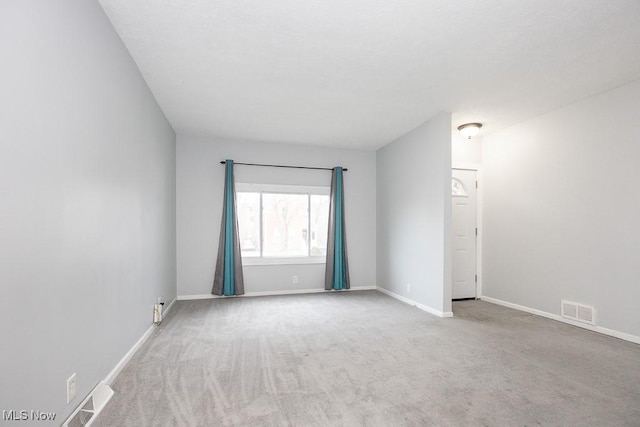 carpeted spare room featuring visible vents and baseboards