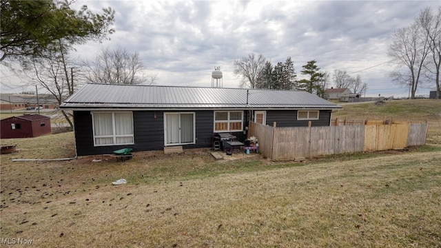 exterior space with fence, metal roof, and a front yard