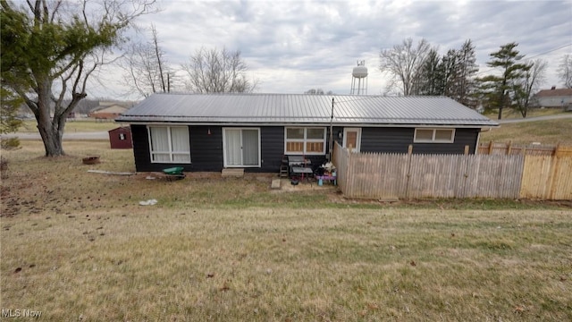 view of front of home featuring metal roof, fence, and a front lawn