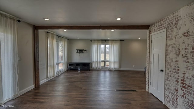 unfurnished living room with brick wall, dark wood-type flooring, visible vents, and baseboards