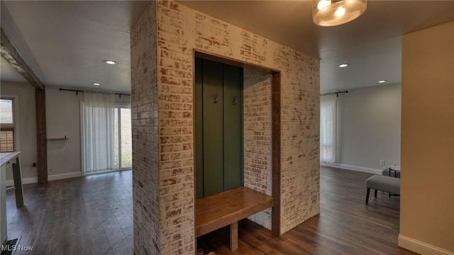 corridor with brick wall, baseboards, dark wood-style flooring, and recessed lighting