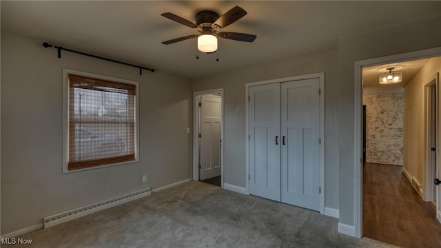 unfurnished bedroom with carpet, a closet, baseboard heating, a ceiling fan, and baseboards