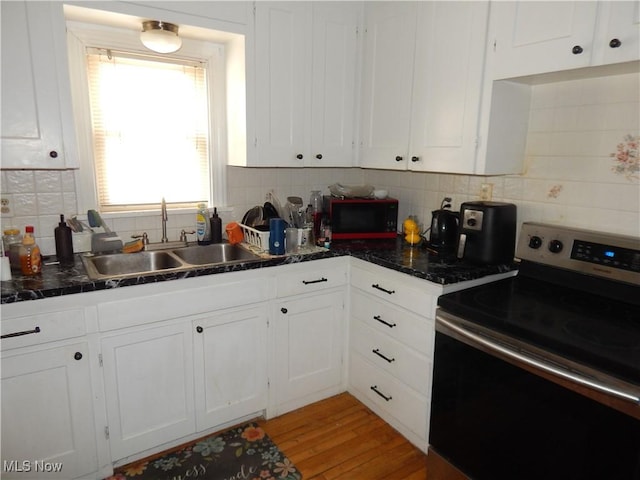 kitchen featuring stainless steel electric stove, light wood-style flooring, white cabinetry, a sink, and black microwave