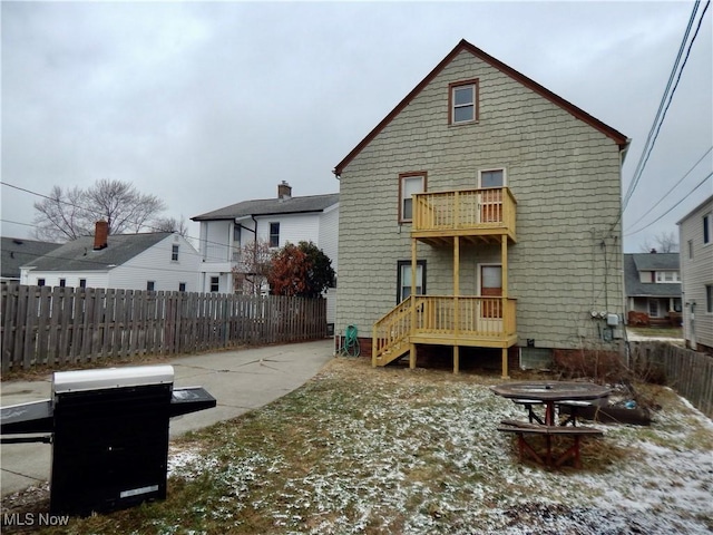 rear view of house featuring a balcony, an outdoor fire pit, and fence