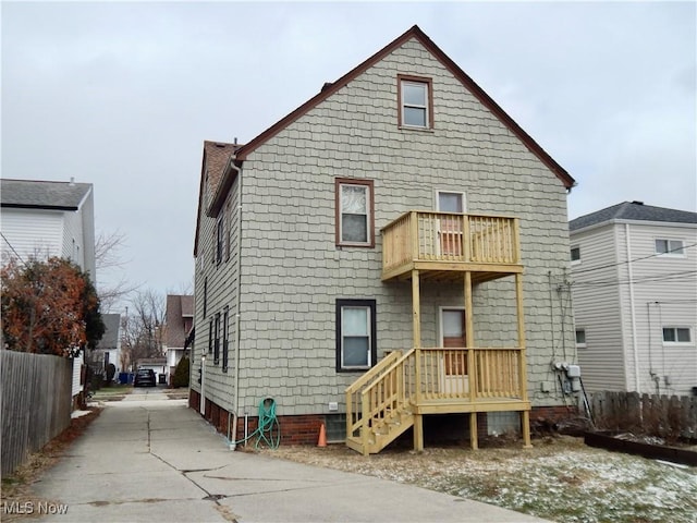 rear view of property featuring a balcony and fence