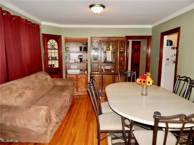 dining area with wood finished floors and crown molding