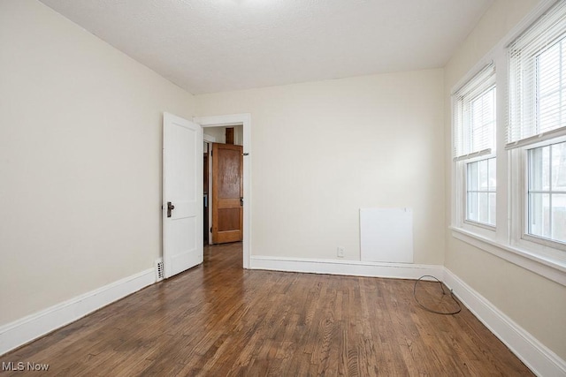 empty room with baseboards and wood finished floors