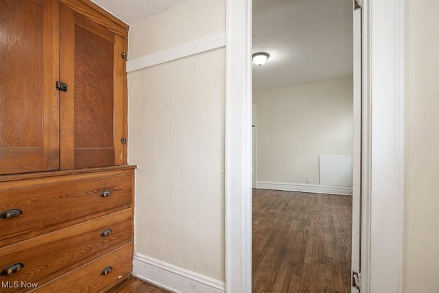 interior space featuring dark wood-style flooring and baseboards