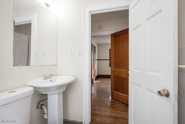 half bath featuring toilet, a sink, and wood finished floors