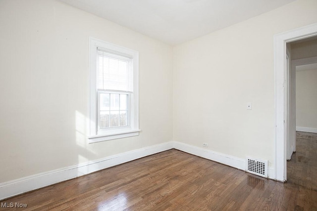 unfurnished room featuring wood finished floors, visible vents, and baseboards