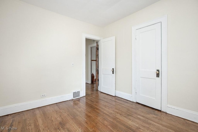 unfurnished bedroom with baseboards, visible vents, and wood finished floors