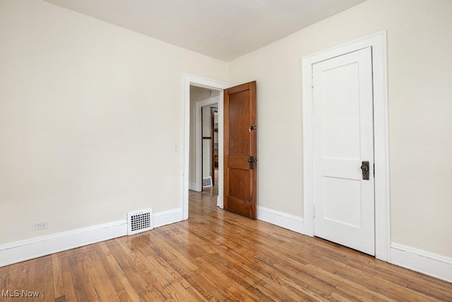 unfurnished room with visible vents, baseboards, and wood finished floors