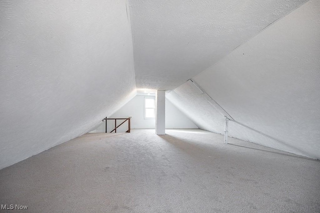 additional living space with a textured ceiling, carpet floors, and lofted ceiling