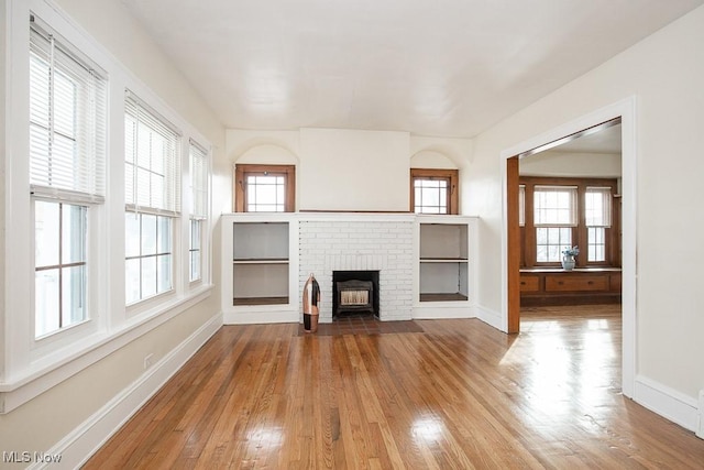 unfurnished living room with a fireplace, baseboards, and wood finished floors