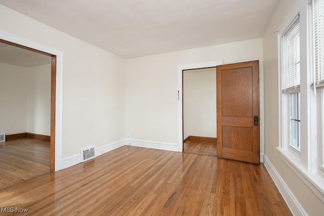 empty room with light wood-style floors, baseboards, and visible vents