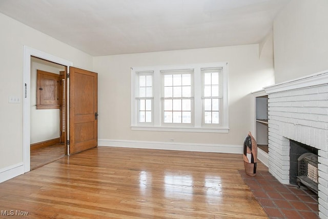 living area featuring light wood-style floors, a fireplace, and baseboards