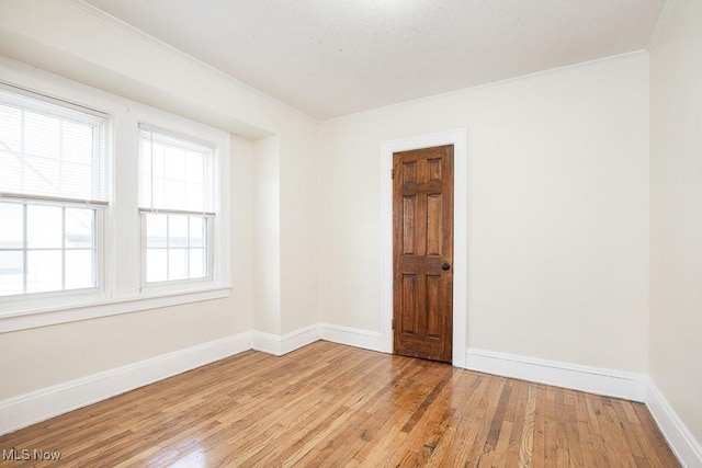 unfurnished room featuring ornamental molding, light wood-type flooring, and baseboards