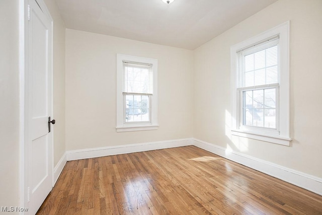 unfurnished room with wood-type flooring, baseboards, and a wealth of natural light