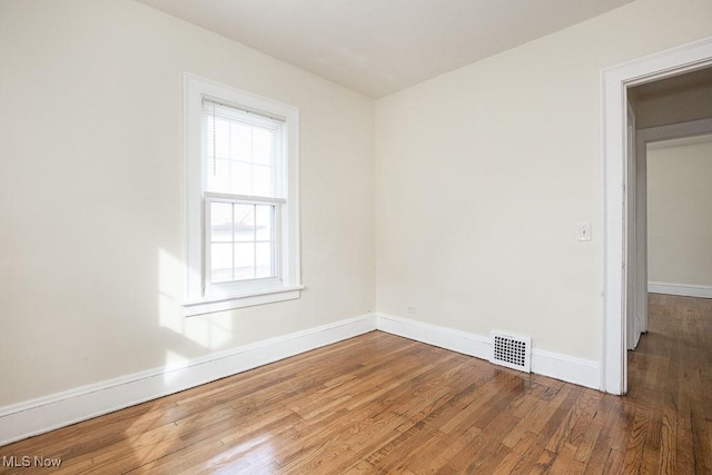 unfurnished room with wood finished floors, visible vents, and baseboards