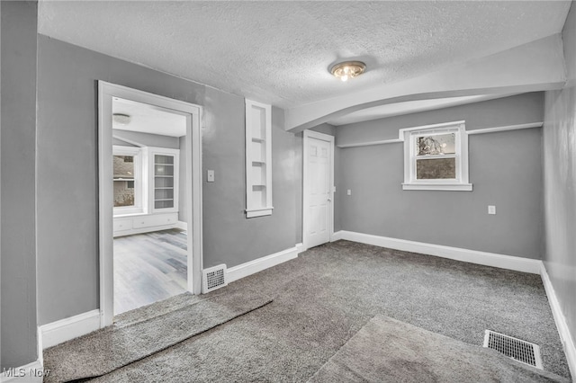 unfurnished room featuring baseboards, visible vents, and arched walkways