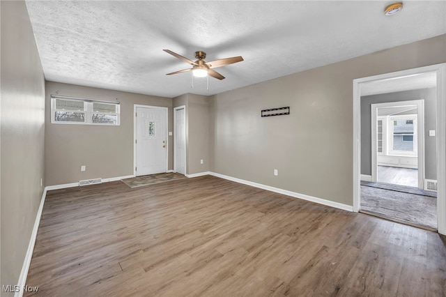 empty room featuring baseboards, wood finished floors, visible vents, and a ceiling fan