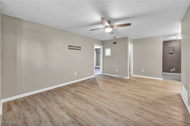 spare room with a textured ceiling, light wood finished floors, a ceiling fan, and baseboards