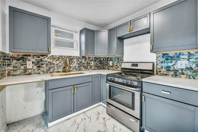 kitchen with stainless steel gas stove, marble finish floor, gray cabinets, and a sink