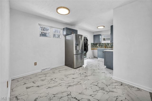 kitchen with visible vents, baseboards, decorative backsplash, stainless steel fridge with ice dispenser, and light countertops